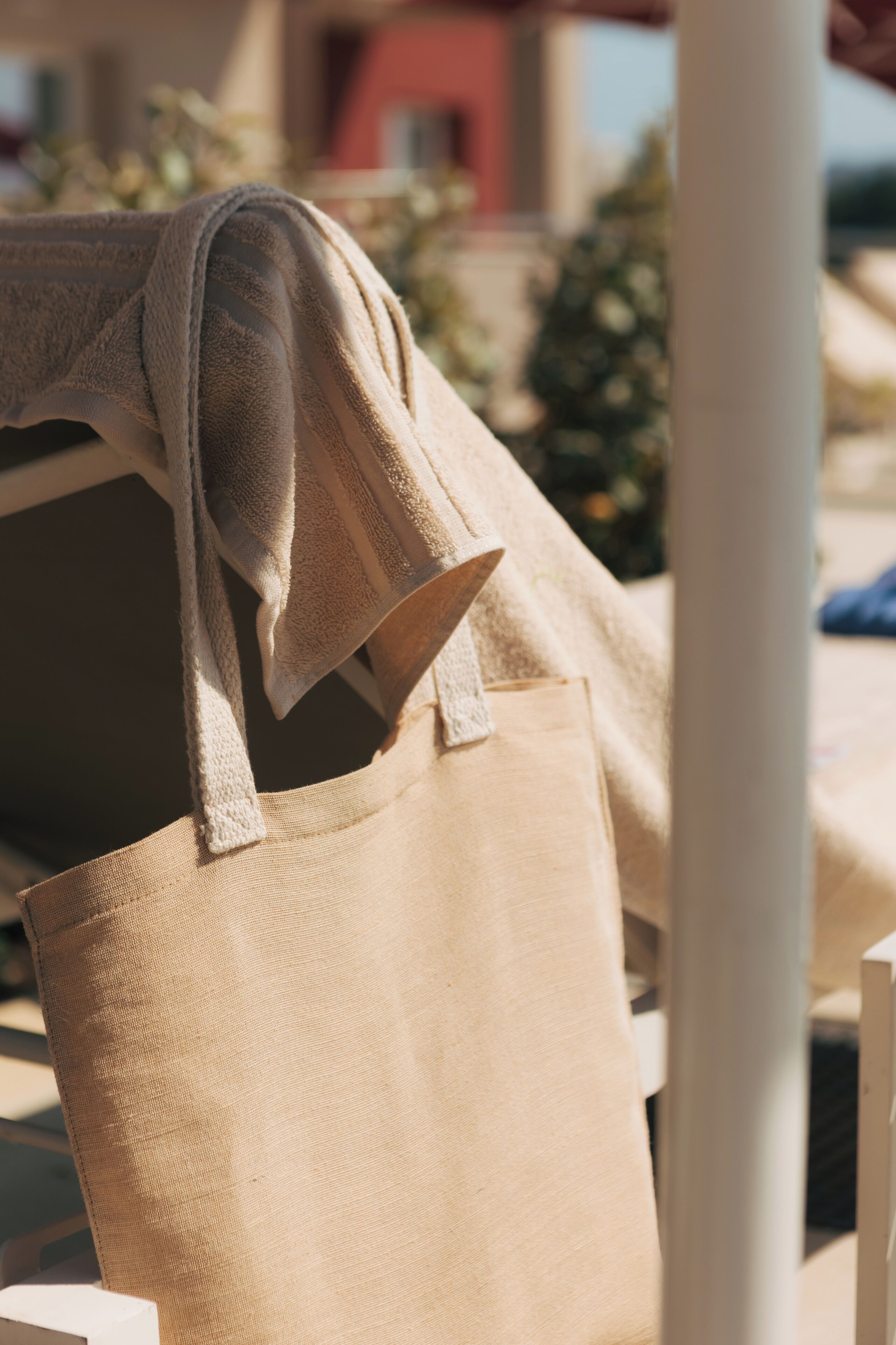 En beige tote-task hænger på en hvid stol.