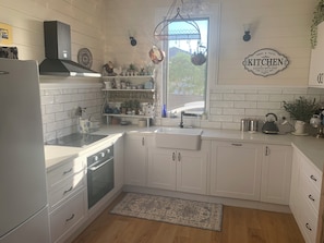 A kitchen with white cabinetry, a stove, a sink, and a window with a view.