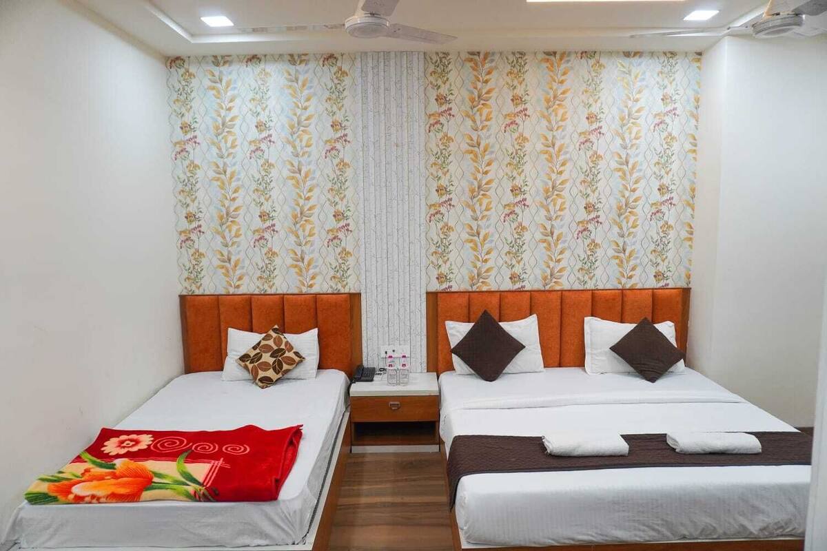 A double room with two beds, each with a wooden headboard, white bedding, and decorative pillows.