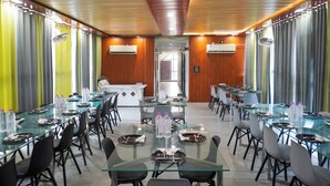 A conference room with glass tables and chairs, air conditioning units, and curtains. - Goyal Hoteliers - Hotel Vasudha (Vrindavan)