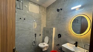 A modern bathroom with a toilet, sink, and shower. - Goyal Hoteliers - Hotel Vasudha (Vrindavan)