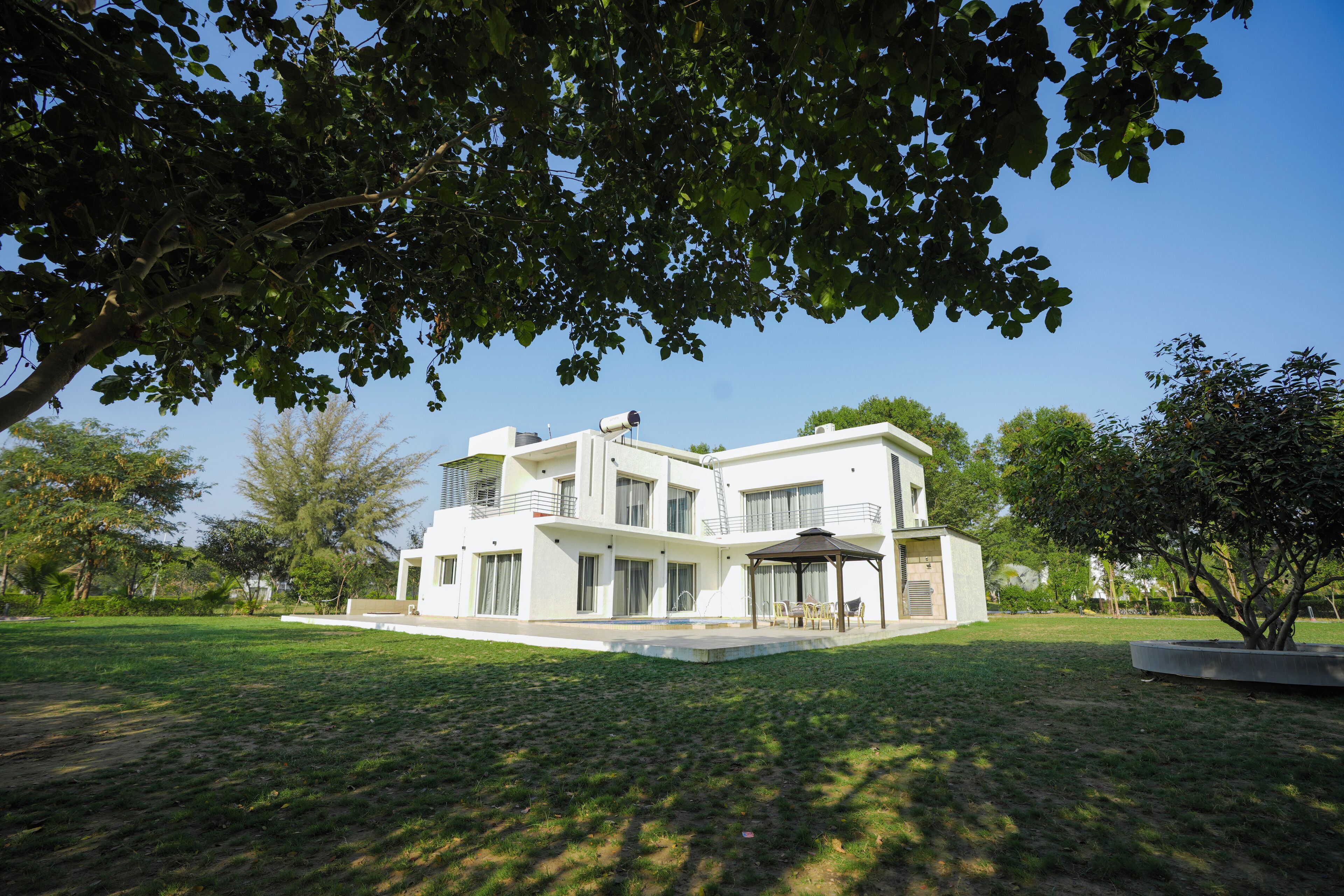Une maison moderne à deux étages, dotée d’une grande pelouse, d’un patio couvert et d’un arbre qui offre de l’ombre.