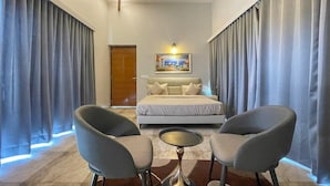 A modern hotel room with a bed, two armchairs, a small round table, and a painting on the wall. - Kings Villa (Bavla)