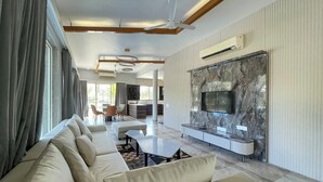 A modern living room with a sofa set, a dining area, and a kitchen in the background. - Kings Villa (Bavla)