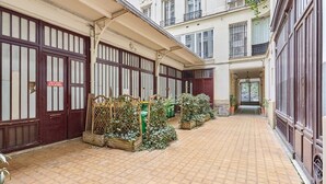 A courtyard with tiled flooring, wooden fences, and potted plants. - Exceptional apartment with AC - Heart of Paris (Paris)
