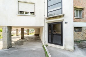 A building with a covered outdoor area, a door with a number plate, and a window with blinds. - GuestHost - Charming 69 sqm apartment, ideal for groups or families of up to 6 people, located on the first floor of a building.The property is in a quiet neighborhood equipped with all essential services and well connected to both the center of Muggia a (Muggia)