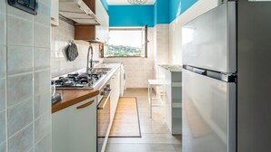 Une cuisine équipée d’une cuisinière, d’un évier et d’un réfrigérateur, une fenêtre avec vue et un plafond bleu.