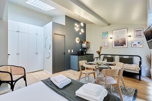 A modern bedroom with a bed, bedside tables, a desk, and a chair. There is a wardrobe, a small kitchenette, and a TV mounted on the wall. - Charming  Studio Center of Paris with AC (Paris)