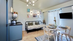 Un espacio habitable compacto con kitchenette, comedor y cama.