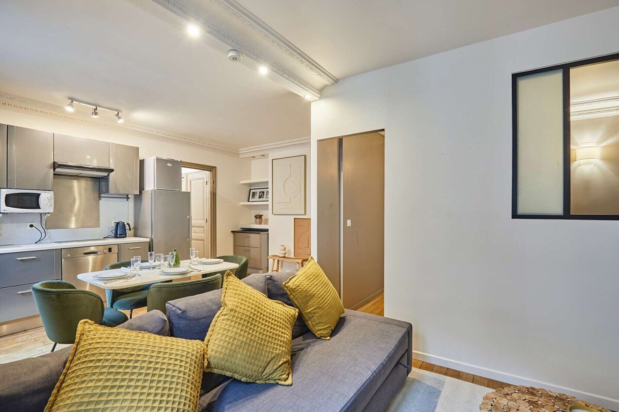 Un appartement moderne doté d’une kitchenette, d’un coin repas et d’un canapé avec des coussins.