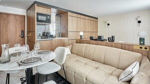 Een moderne keuken met houten kastjes, een ingebouwde magnetron en een eethoek met een marmeren tafel en een beige bank.