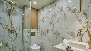 A modern bathroom with a glass-enclosed shower, a toilet, and a sink with a gold faucet. - New apartment Center of Paris/Le Marais (Paris)