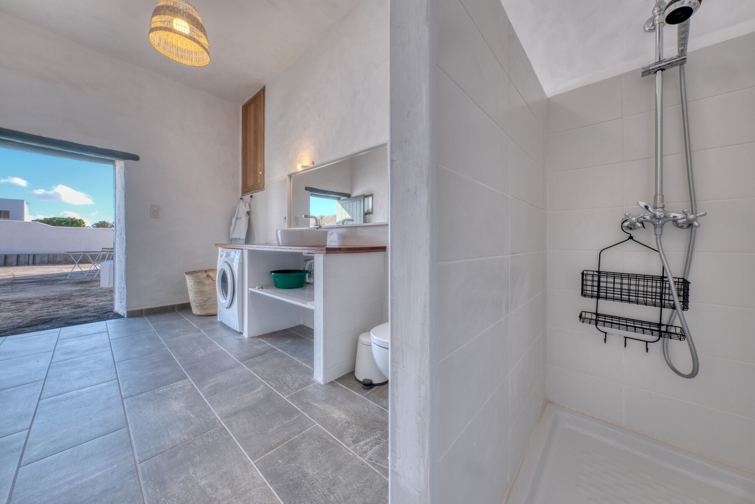 A modern bathroom with a shower, a toilet, a sink, and a laundry area.