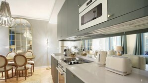 Una cocina moderna con una isla central, horno empotrado y un comedor con candelabro.