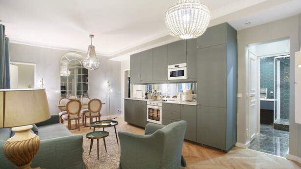 Una cocina moderna con armarios grises, un microondas y un comedor con candelabro.