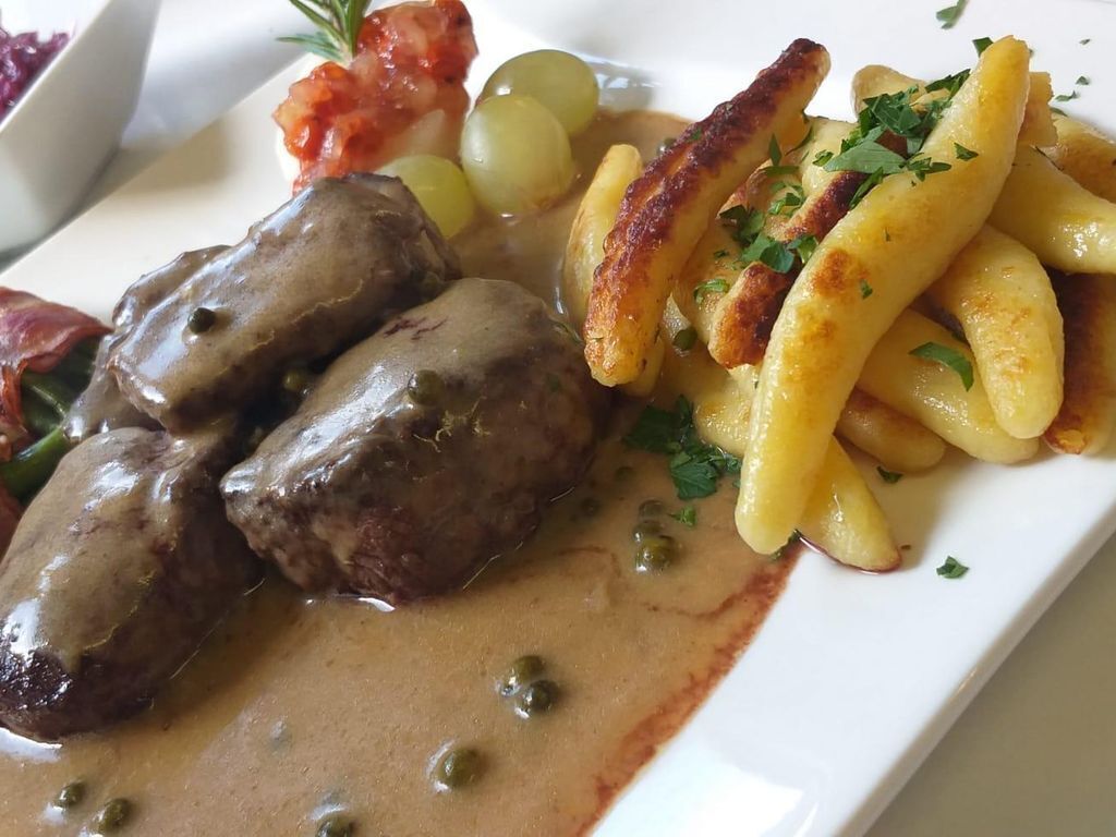 Un plato de albóndigas en salsa, patatas y una guarnición.