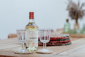 A bottle of chardonnay and two glasses on a wooden table.