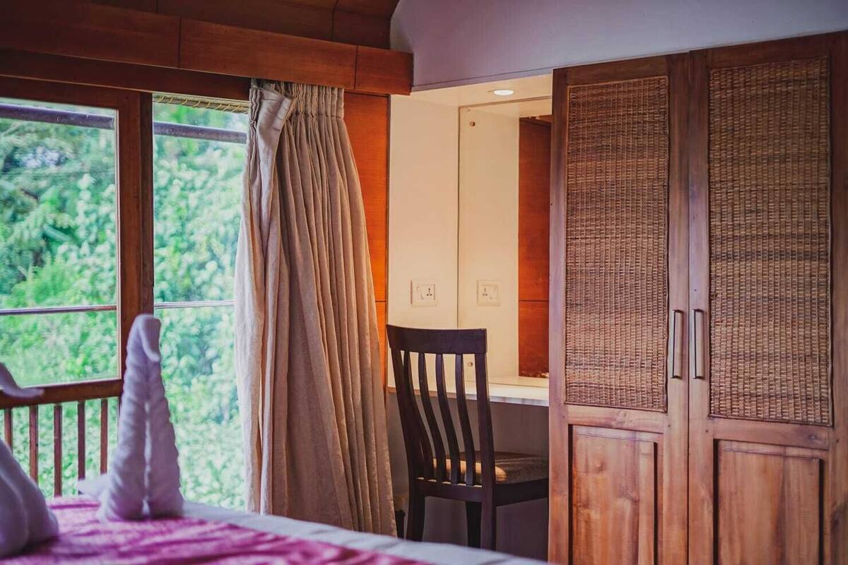 A room with a bed, a chair, a window with curtains, and wooden cabinets.