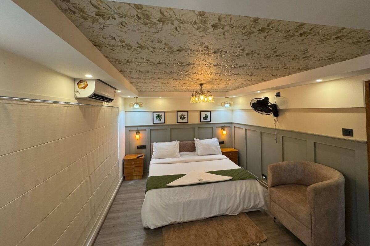 A bedroom with a bed, bedside tables, a chair, a ceiling fan, and a wall-mounted air conditioner.