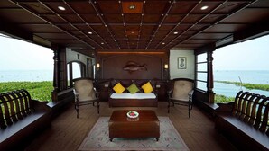 A room with a bed, two armchairs, a coffee table, and a view of the sea. - The Boat Company (Cherthala)