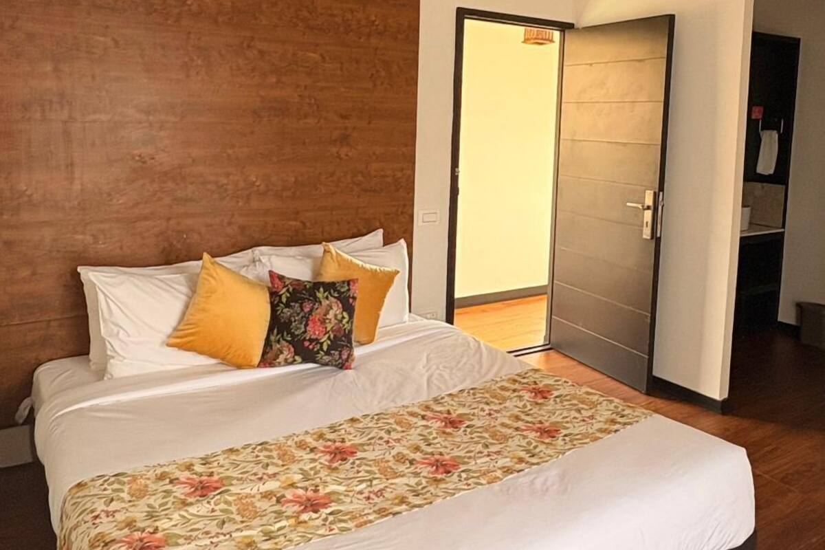 A bedroom with a large bed, wooden ceiling, and a ceiling fan.