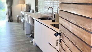 Een moderne keuken met een houten accentmuur, een inbouweiland met barkrukken en uitzicht op de omgeving.