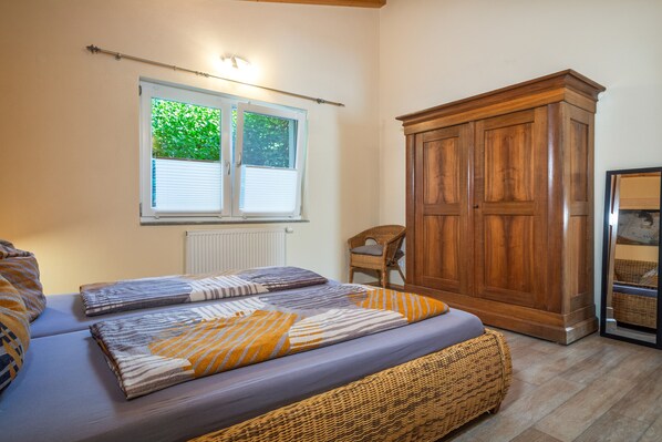 Un dormitorio con cama, armario, ventana con persianas y una silla.