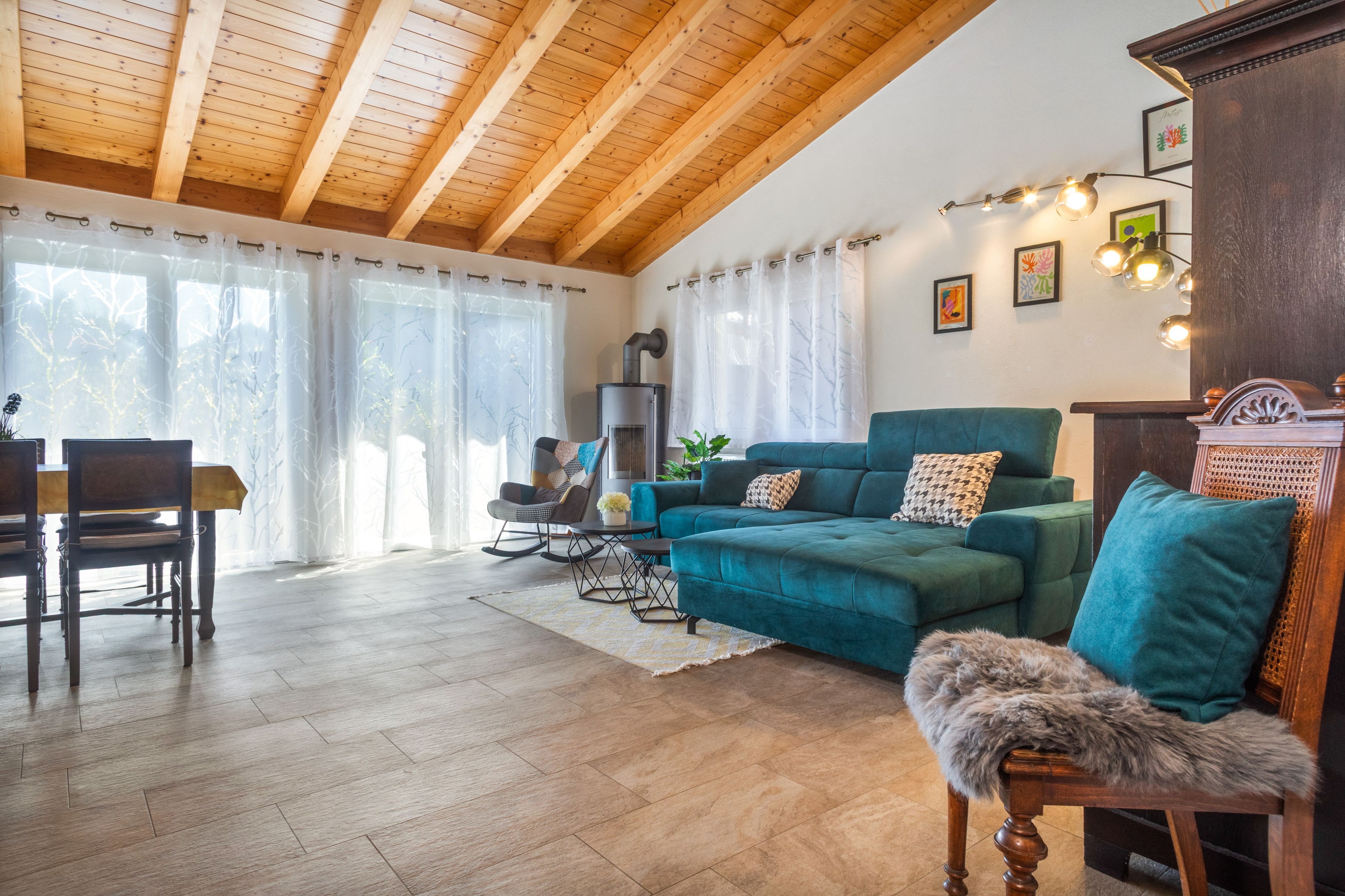Ein gemütliches Wohnzimmer mit Holzbalkendecke, einer Couch, einem Sessel und einem Tisch.