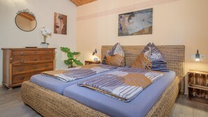Ein Schlafzimmer mit einem Bett, einem Schminktisch, einem Spiegel und Bildern an den Wänden.