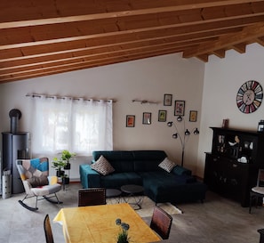 A living room with a sofa, a dining table, a fireplace, and a clock on the wall.