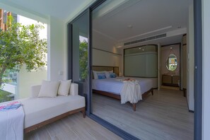 A modern bedroom with a large bed, a sofa, and a sliding glass door leading to a balcony. - InterContinental Residences 2Bedroom IRA (Hua Hin)