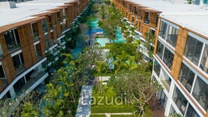 A modern hotel with a central swimming pool surrounded by lush greenery and multiple buildings with large windows. - InterContinental Residences 2Bedroom IRA (Hua Hin)