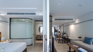A modern hotel room with a bed, a sofa, a dining area, and a kitchen in the background. - InterContinental Residences 2Bedroom IRA (Hua Hin)