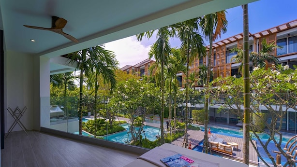 A modern hotel room with a large window overlooking a pool and lush greenery. - InterContinental Residences 2Bedroom IRA (Hua Hin)
