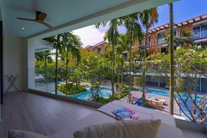 A modern hotel room with a large window overlooking a pool and lush greenery. - InterContinental Residences 2Bedroom IRA (Hua Hin)