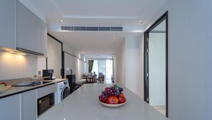 A modern kitchen with a marble countertop, a washing machine, and a dining area with a table and chairs. - InterContinental Residences 2Bedroom IRA (Hua Hin)