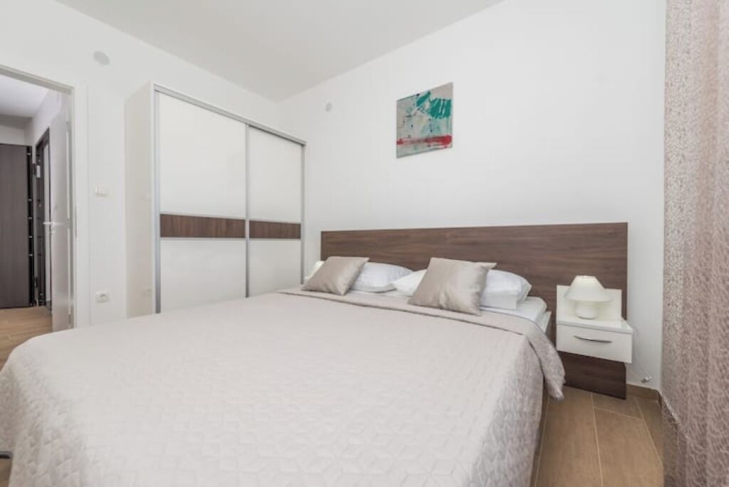 A bedroom with a bed, a nightstand, a wardrobe, and a wall-mounted artwork.
