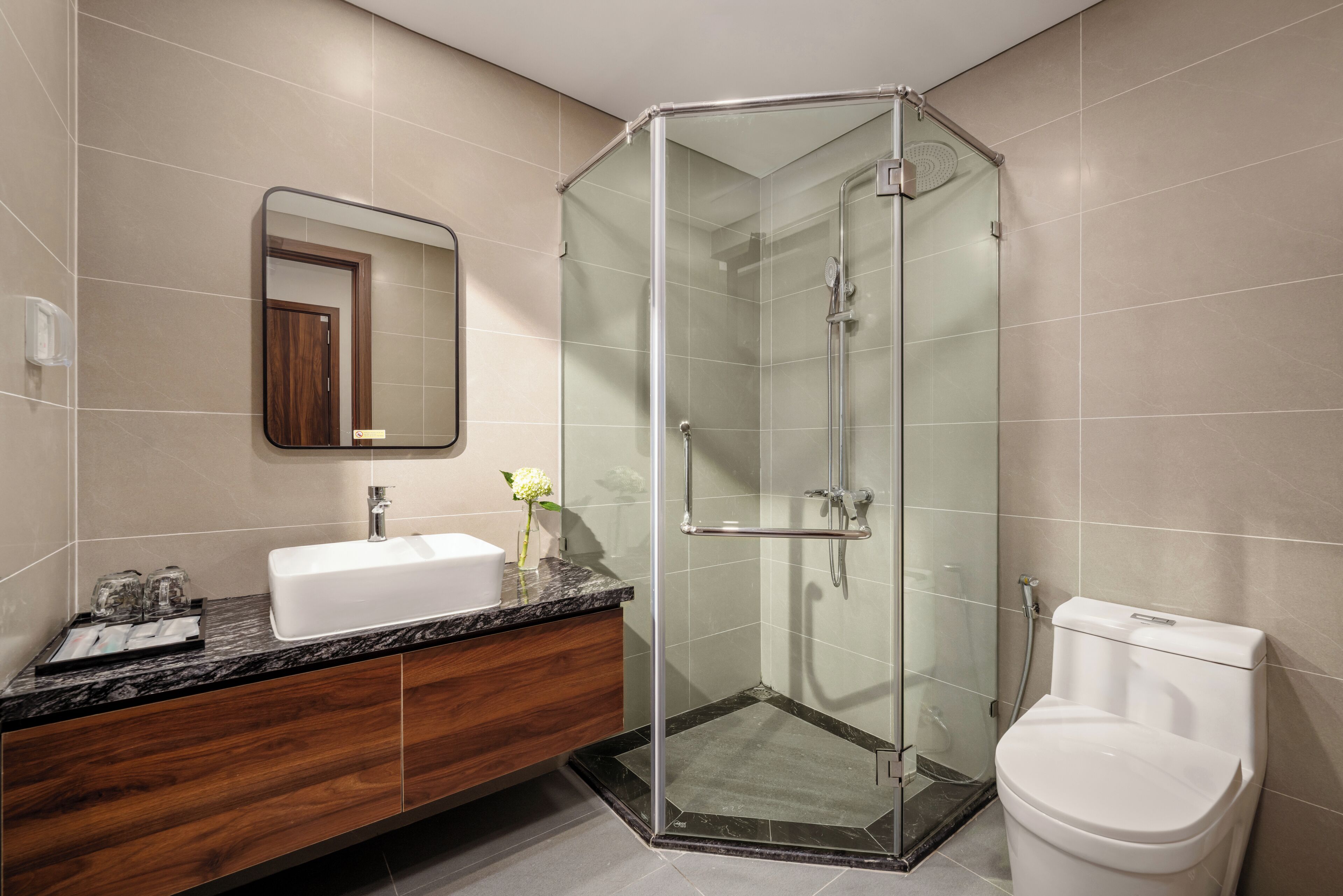 A modern bathroom with a glass-enclosed shower, a white sink, and a toilet.