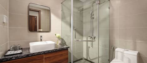 A modern bathroom with a glass-enclosed shower, a white sink, and a toilet.