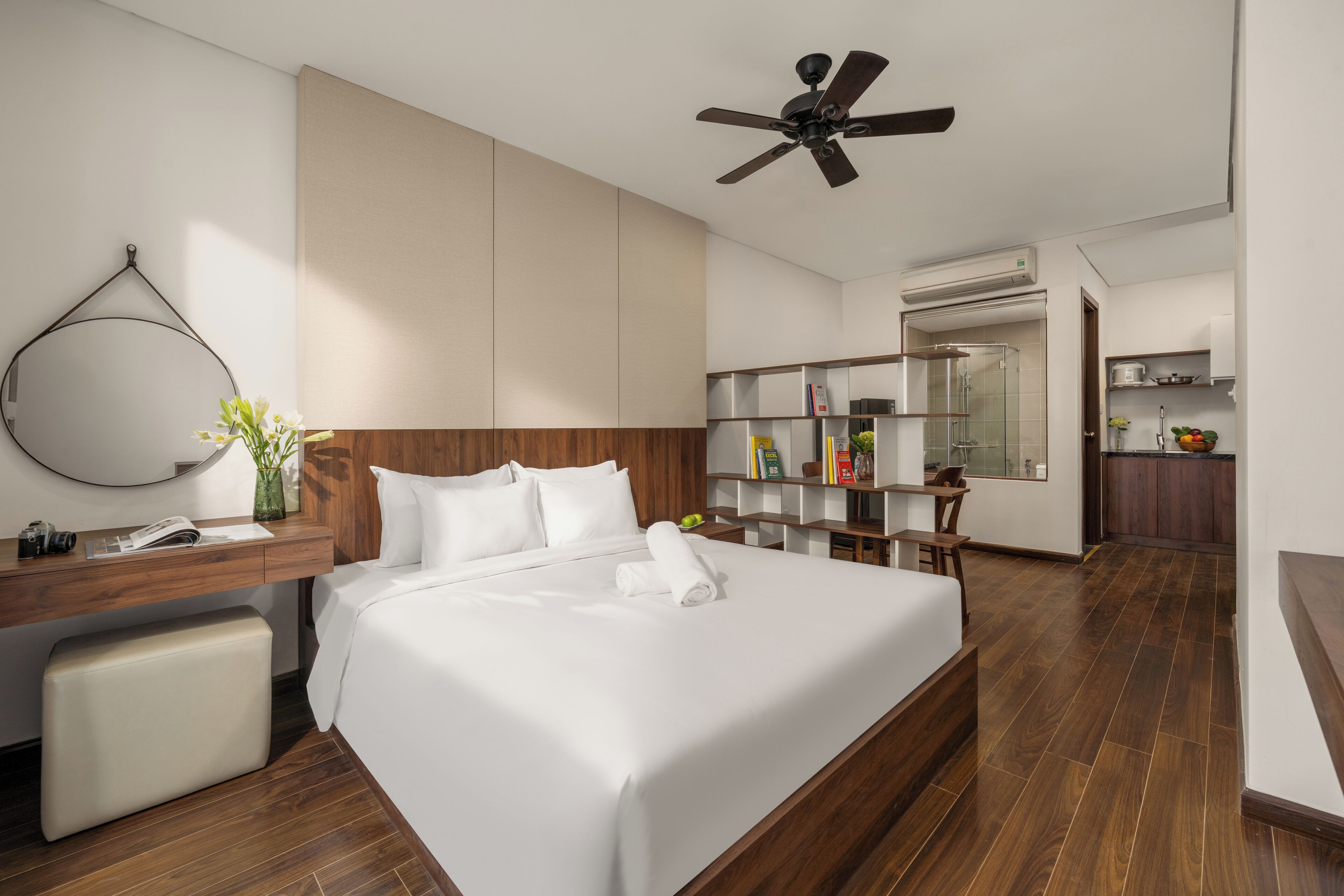 Une chambre d’hôtel moderne dotée d’un grand lit, d’un bureau avec une chaise, d’une coiffeuse et d’une kitchenette.