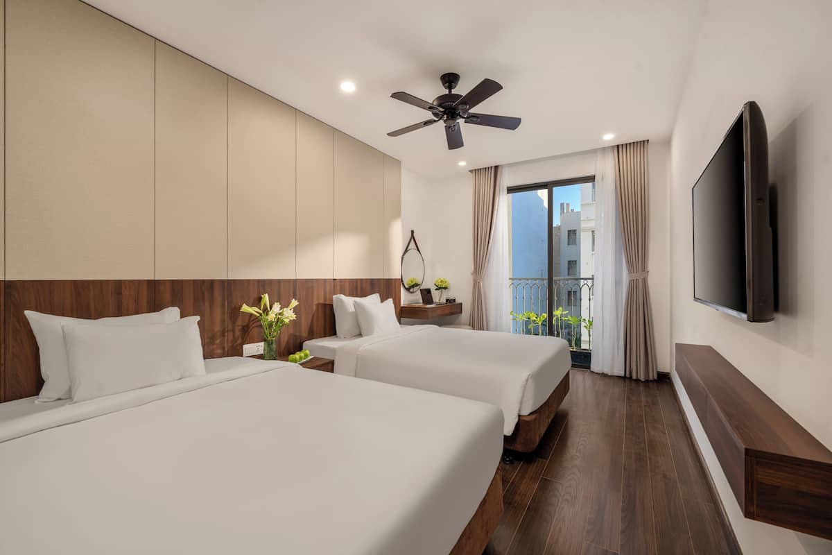A hotel room with two beds, a ceiling fan, a TV, and a balcony with a view.