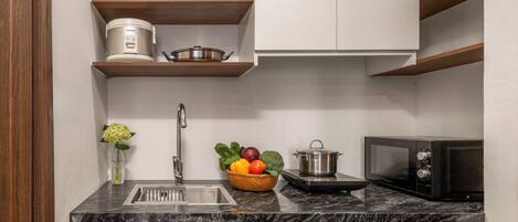 A kitchen with a sink, a microwave, a stove, and a fruit bowl on the counter.