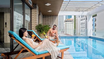 A poolside area with lounge chairs, a clear view of the cityscape, and a modern building facade.