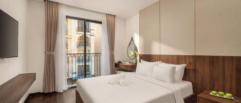 Une chambre d’hôtel avec un grand lit, une table de chevet avec des pommes, une télévision et un balcon avec des rideaux.