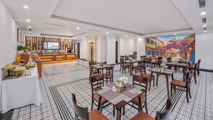 Ein Hotel-Speisebereich mit mehreren Tischen, Stühlen, einem Buffet und einem Wandgemälde.