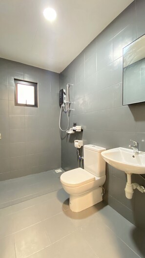 Ein modernes Badezimmer mit grauen Fliesen, einer Toilette, einem Waschbecken und einer Dusche.