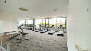 Ett gym med löpband, crosstrainers och träningsbänkar för styrketräning.