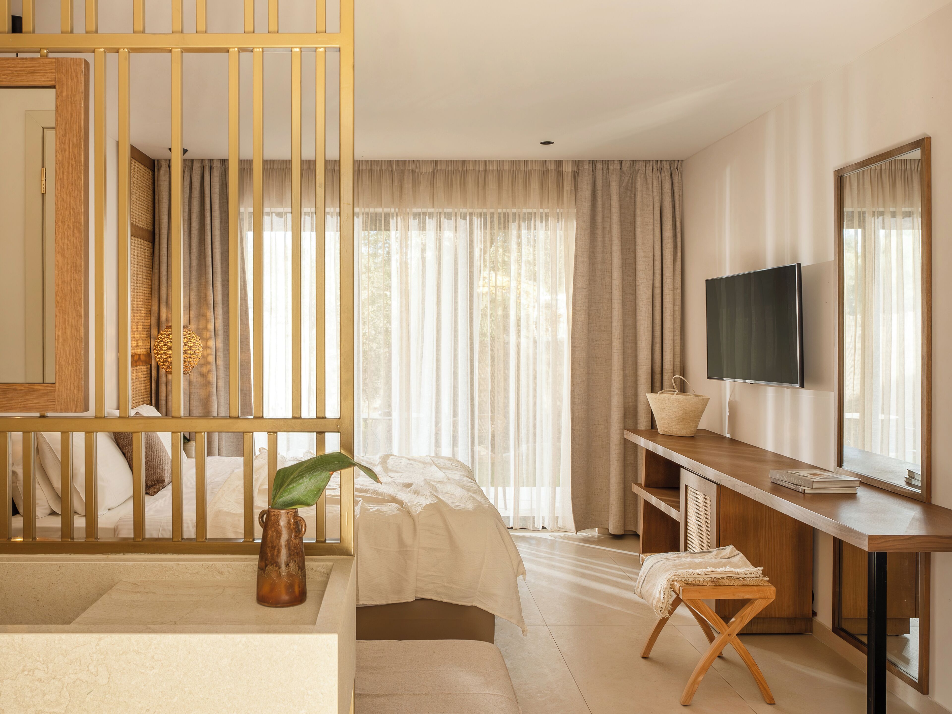A modern hotel room with a bed, a desk, a TV, and a large window with curtains.