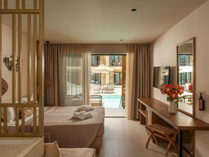 A hotel room with a bed, a desk, a chair, a TV, and a view of a pool and outdoor seating. - Ekati Mare Lifestyle Resort (Corfu)
