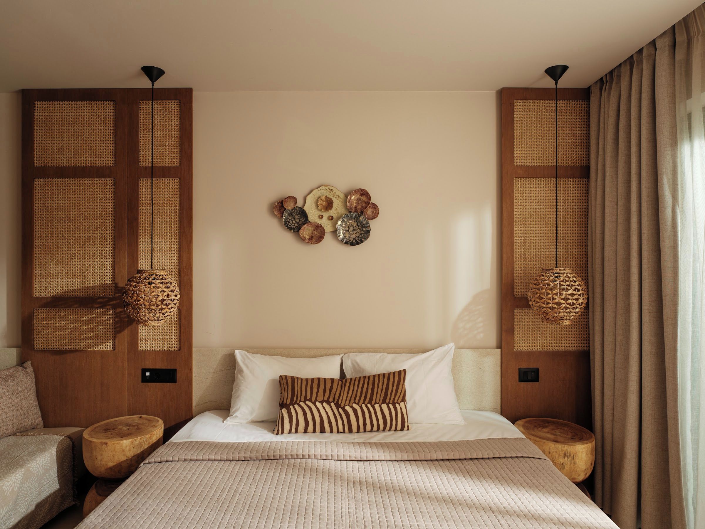 A hotel room with a large bed, two wooden nightstands, a wall-mounted lamp, and a decorative wall piece.